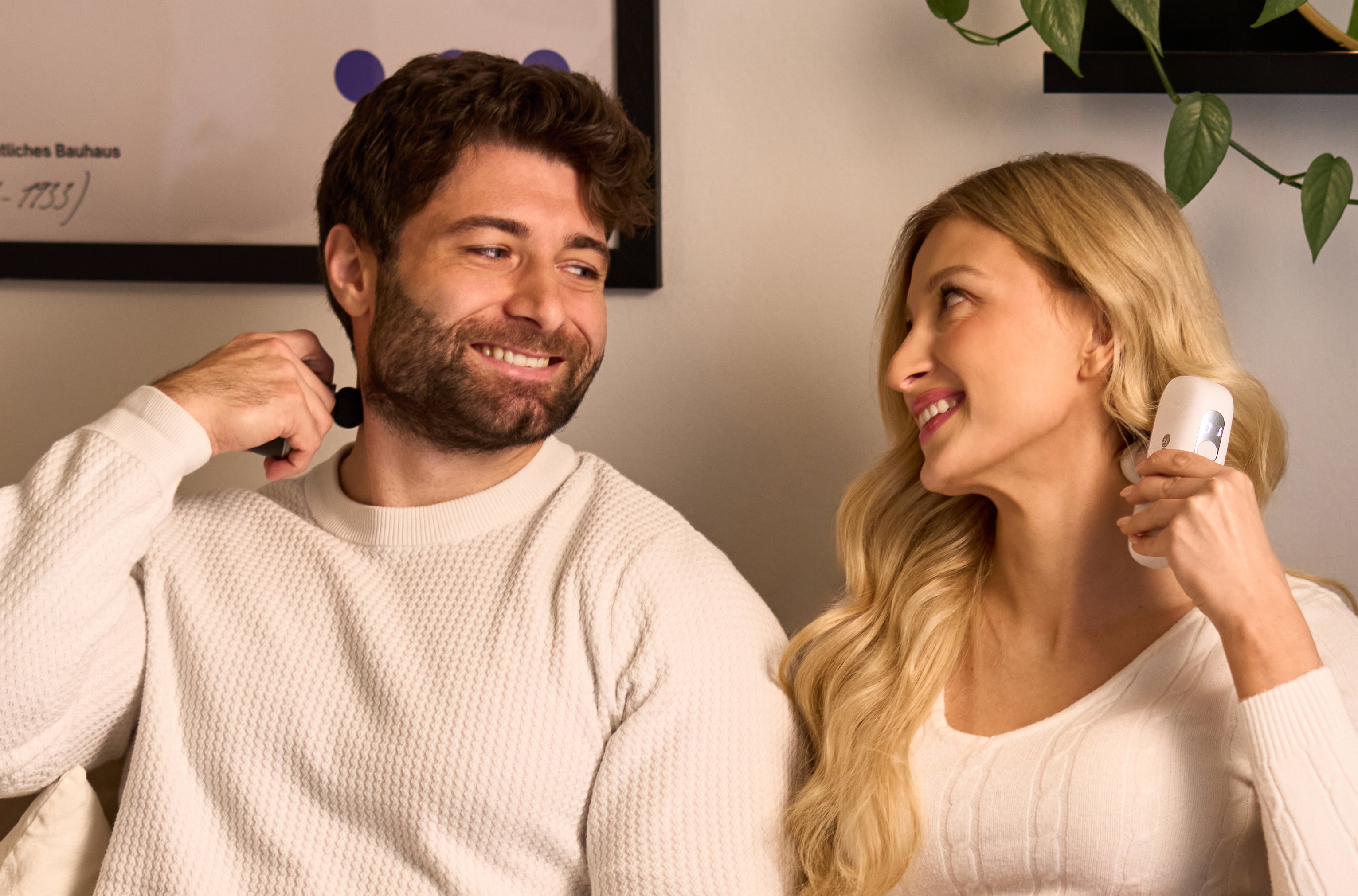 Na zdjęciu siedzący obok siebie mężczyzna i kobieta, którzy patrzą sobie w oczy z uśmiechem. Oboje masują kark ZENT MiniPulse™ – Masażerem Uderzeniowym w Kompaktowej Formie