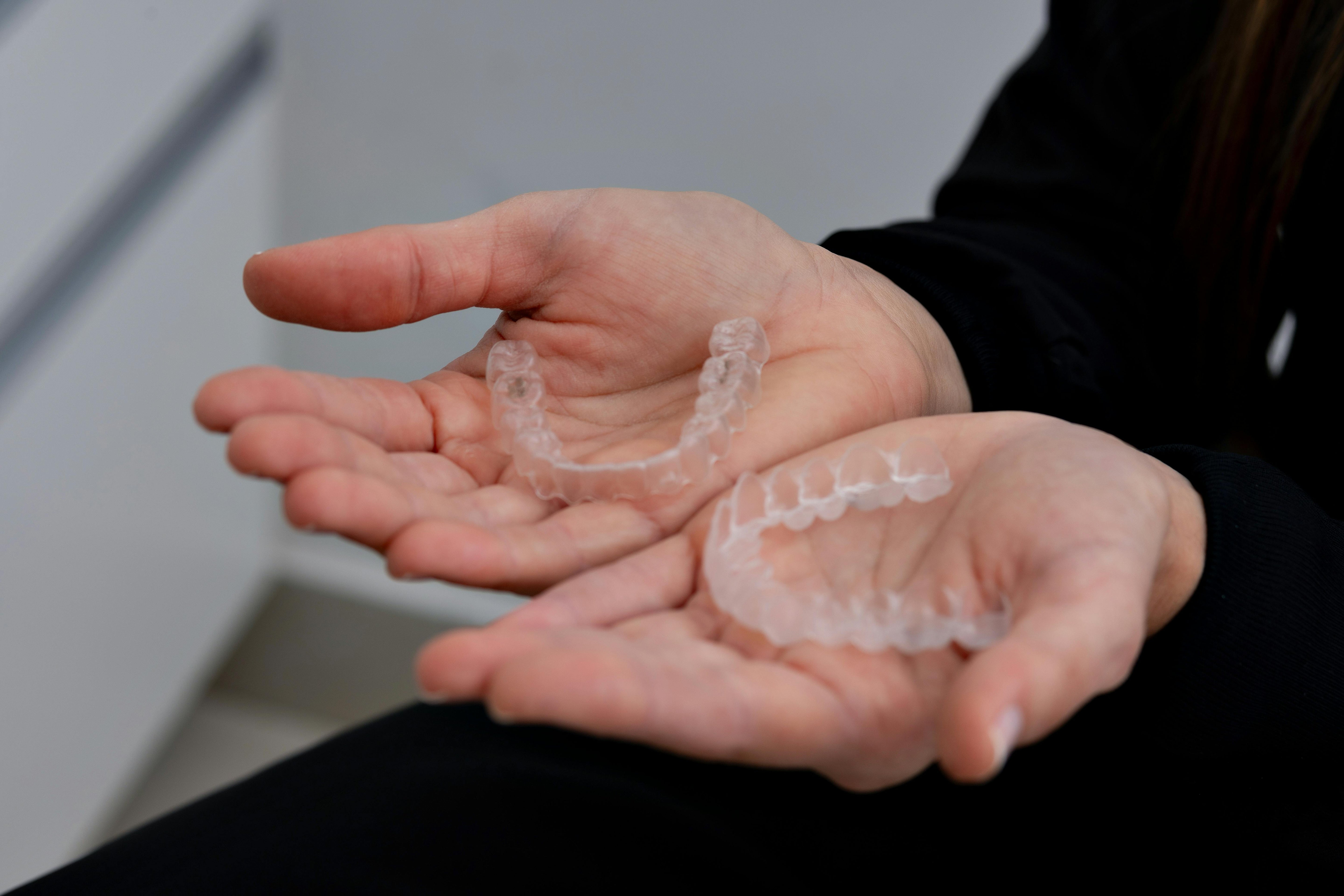 Nakładki invisalign trzymane w dłoniach mężczyzny. Jak je czyścić?